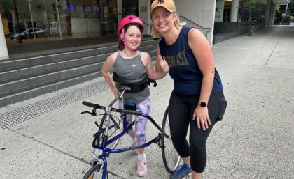 Young girl on running frame with mother standing beside her. Image, UQ